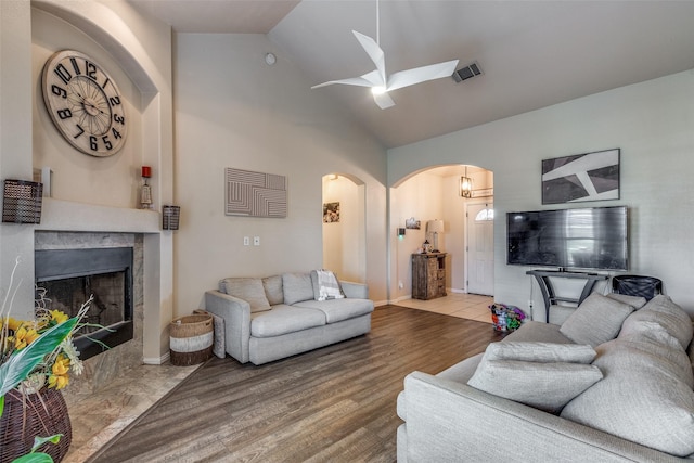 living room featuring hardwood / wood-style flooring, a premium fireplace, high vaulted ceiling, and ceiling fan