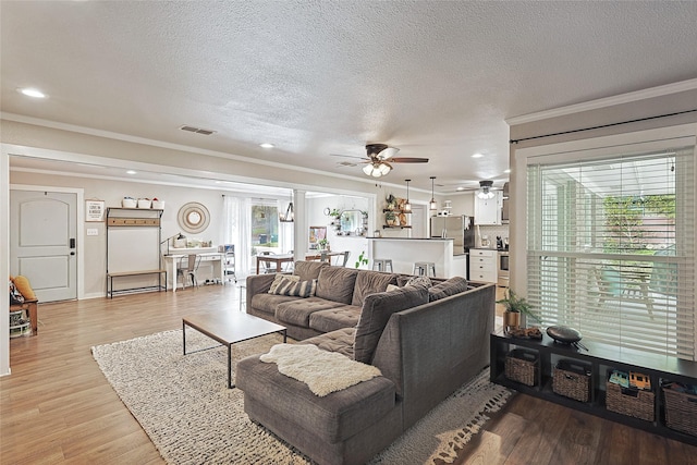 living room with ornamental molding, light hardwood / wood-style floors, and a healthy amount of sunlight