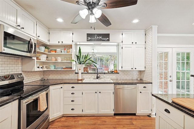 kitchen featuring backsplash, ornamental molding, stainless steel appliances, light hardwood / wood-style flooring, and white cabinetry