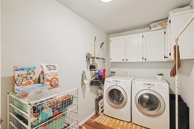 washroom with hardwood / wood-style floors, cabinets, and washing machine and clothes dryer