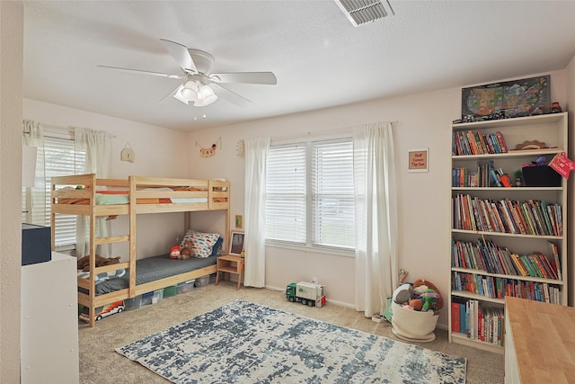 carpeted bedroom with multiple windows, ceiling fan, and a textured ceiling