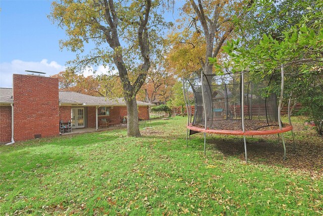 view of yard featuring a trampoline and a patio