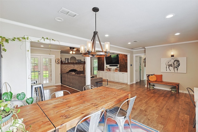 dining room with a fireplace, ornamental molding, ceiling fan with notable chandelier, and hardwood / wood-style flooring