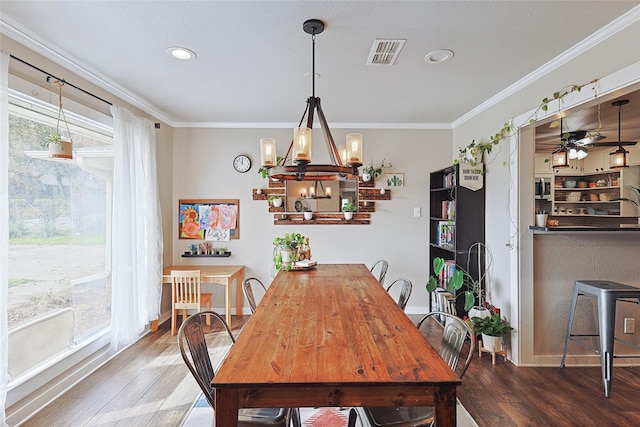 dining room with crown molding, plenty of natural light, wood-type flooring, and ceiling fan with notable chandelier