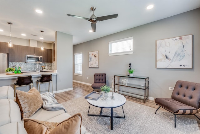 living room with light hardwood / wood-style flooring and ceiling fan