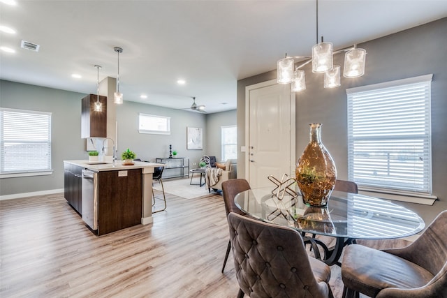 dining room featuring ceiling fan, light hardwood / wood-style floors, a wealth of natural light, and sink