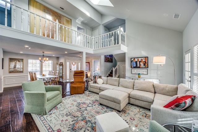 living room featuring an inviting chandelier, a towering ceiling, and hardwood / wood-style flooring