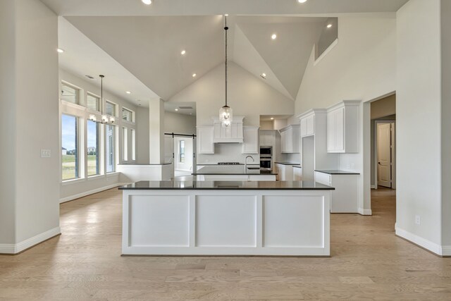 kitchen with a barn door, pendant lighting, white cabinets, and a spacious island