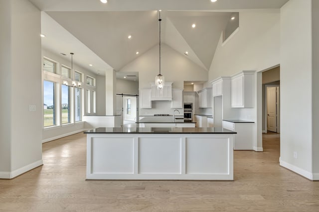 kitchen featuring hanging light fixtures, white cabinets, light wood-type flooring, and a spacious island