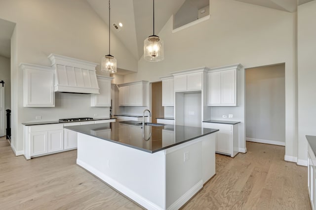 kitchen featuring sink, white cabinetry, decorative light fixtures, a center island with sink, and stainless steel gas stovetop