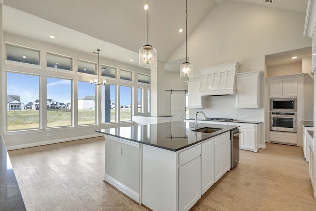 kitchen featuring premium range hood, decorative light fixtures, stainless steel appliances, a barn door, and white cabinets