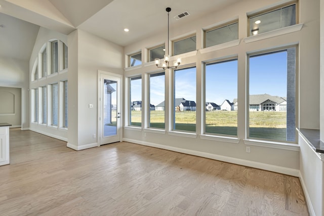 interior space with light hardwood / wood-style flooring, high vaulted ceiling, and an inviting chandelier