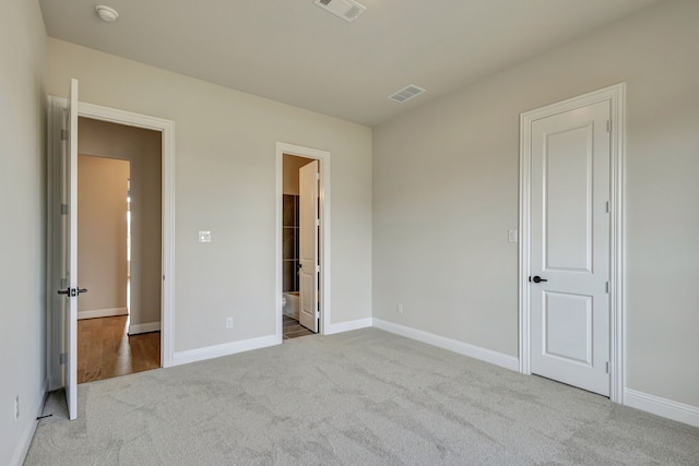 unfurnished bedroom with ensuite bath and light carpet