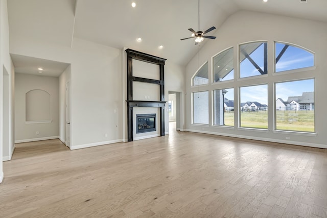 unfurnished living room with ceiling fan, high vaulted ceiling, and light hardwood / wood-style floors