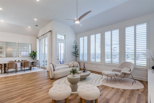 living room with lofted ceiling, a wealth of natural light, and light hardwood / wood-style flooring