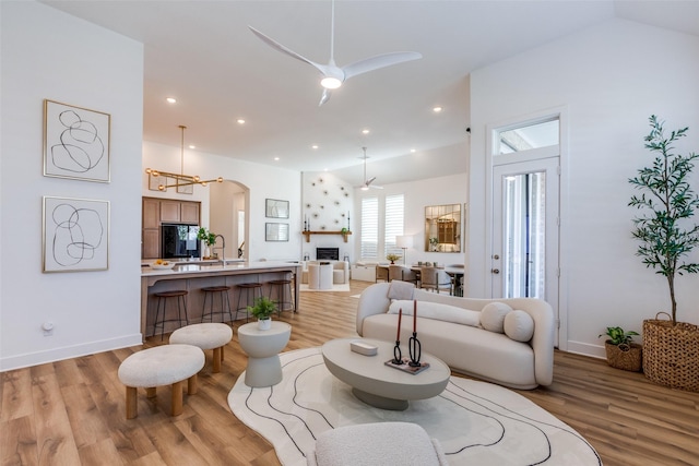 living room with ceiling fan, lofted ceiling, and light hardwood / wood-style flooring