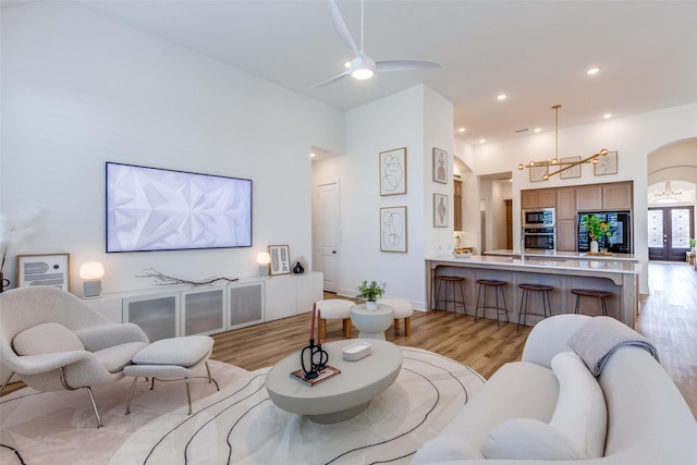 living room featuring ceiling fan with notable chandelier and light wood-type flooring