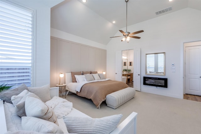 bedroom featuring ceiling fan, high vaulted ceiling, ensuite bathroom, and light wood-type flooring