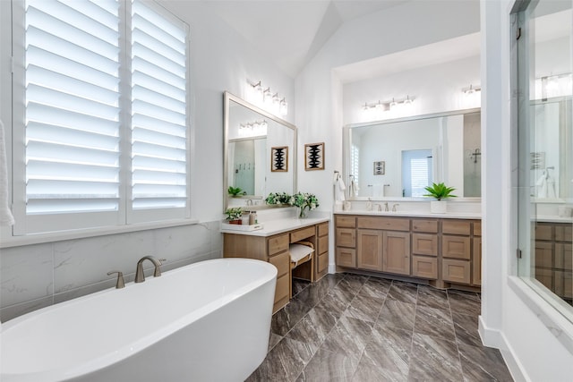 bathroom with vanity, vaulted ceiling, a wealth of natural light, and a tub