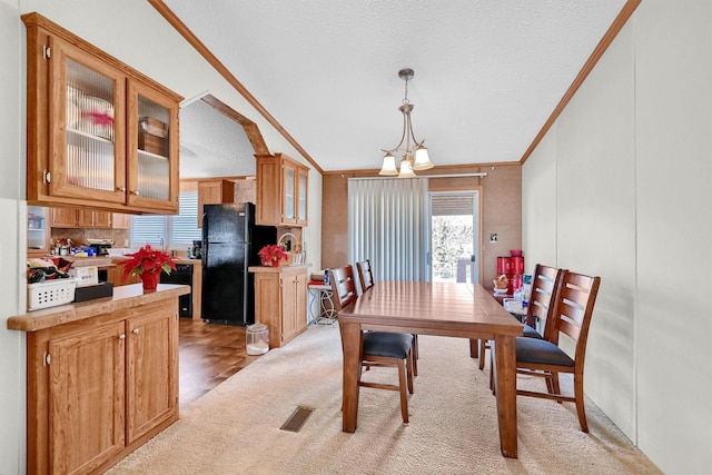 dining room with a chandelier, a textured ceiling, crown molding, and lofted ceiling