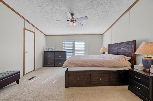 bedroom with ceiling fan, light colored carpet, a textured ceiling, and crown molding