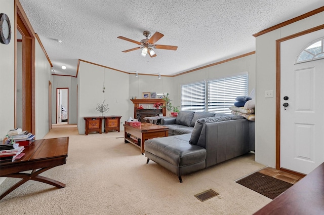 living room featuring light carpet, a textured ceiling, ceiling fan, and crown molding