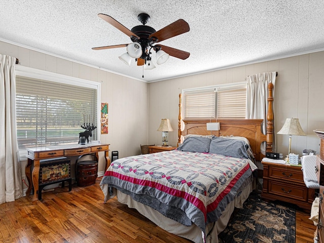 bedroom with dark wood-type flooring, ornamental molding, and a textured ceiling