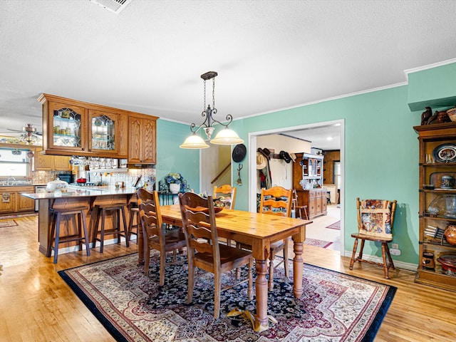 dining area with crown molding, ceiling fan, a textured ceiling, and light wood-type flooring