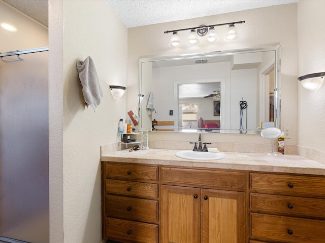 bathroom featuring walk in shower, vanity, and a textured ceiling