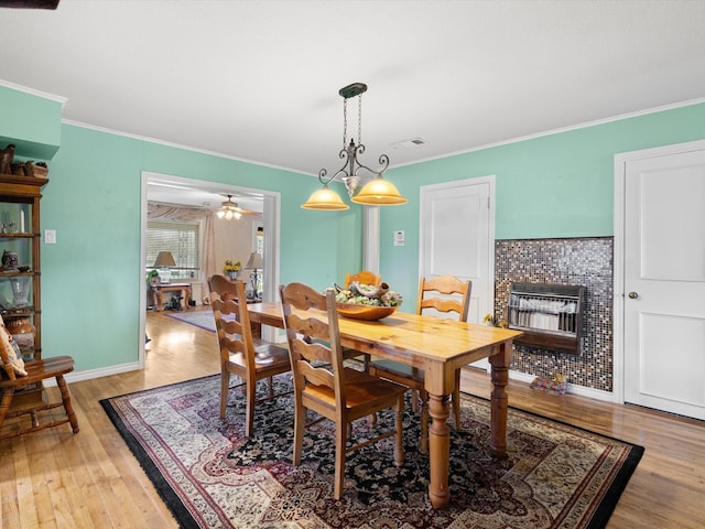 dining area featuring a tiled fireplace, crown molding, and hardwood / wood-style flooring