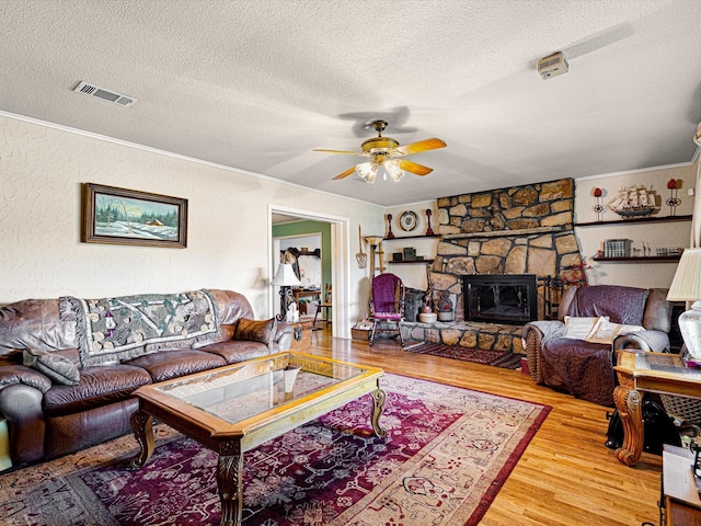 living room with a fireplace, crown molding, wood-type flooring, and a textured ceiling