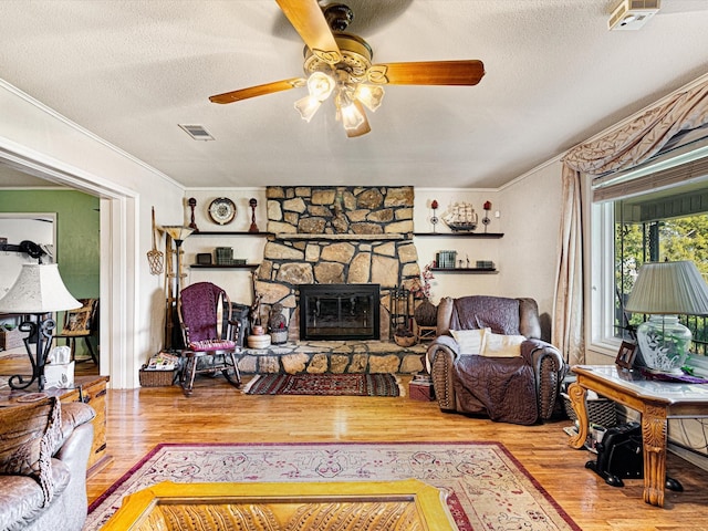 living room with crown molding, hardwood / wood-style floors, a textured ceiling, and a fireplace