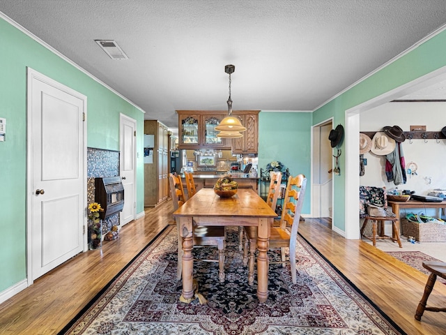 dining space with crown molding, hardwood / wood-style floors, a textured ceiling, and a fireplace