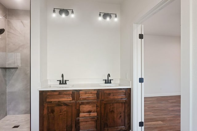 bathroom featuring vanity, wood-type flooring, and tiled shower