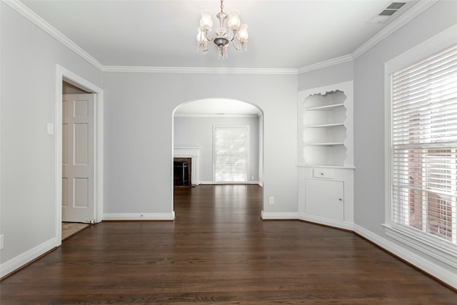 unfurnished dining area with a notable chandelier, crown molding, dark wood-type flooring, and built in features