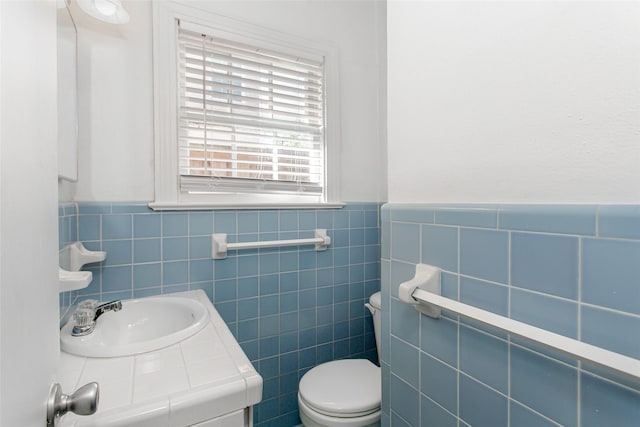 bathroom with sink, tile walls, and toilet