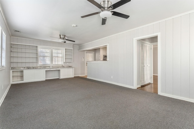 unfurnished living room with ceiling fan, dark carpet, and ornamental molding