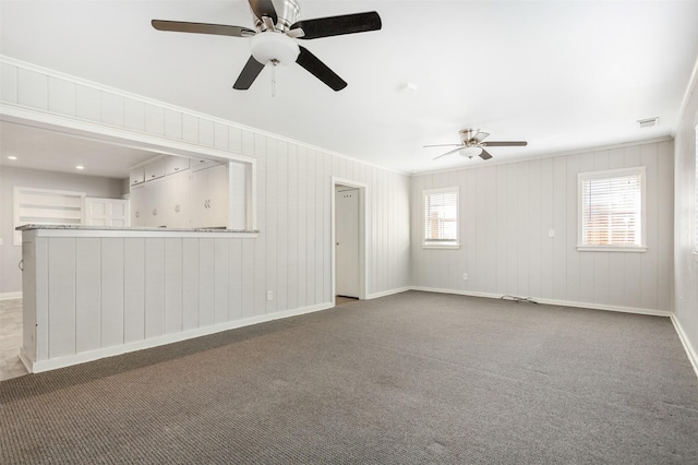 carpeted spare room featuring crown molding, ceiling fan, and wood walls