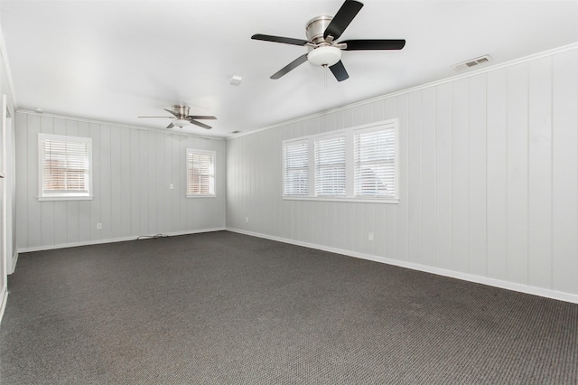 unfurnished room with ceiling fan, a healthy amount of sunlight, and dark colored carpet