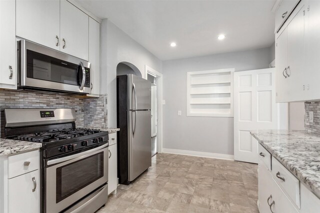 kitchen featuring light stone counters, white cabinetry, backsplash, and appliances with stainless steel finishes