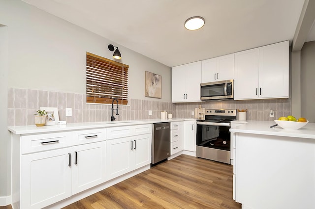 kitchen featuring stainless steel appliances, white cabinetry, light hardwood / wood-style floors, and sink