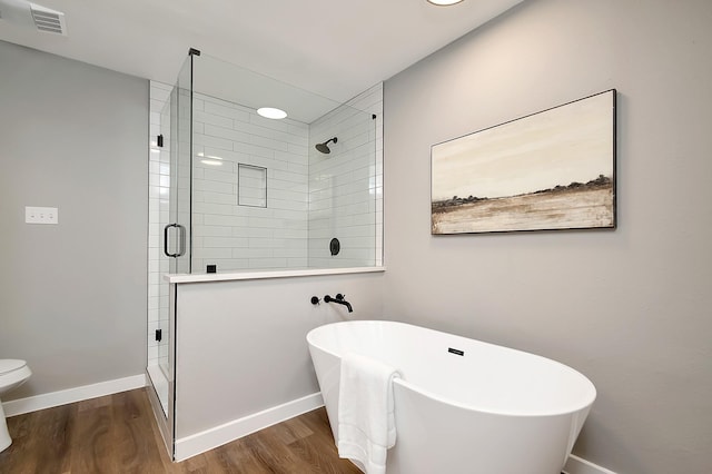 bathroom with toilet, plus walk in shower, and hardwood / wood-style flooring