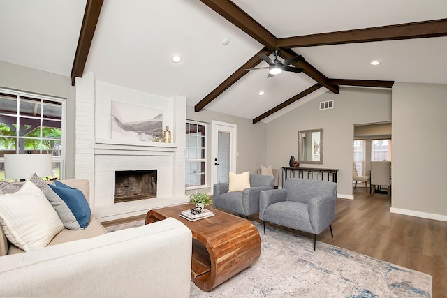 living room with hardwood / wood-style floors, lofted ceiling with beams, ceiling fan, and a brick fireplace