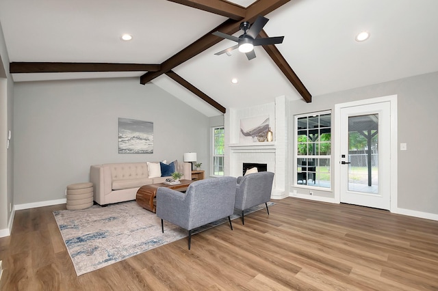 living room with lofted ceiling with beams, a fireplace, ceiling fan, and light hardwood / wood-style floors