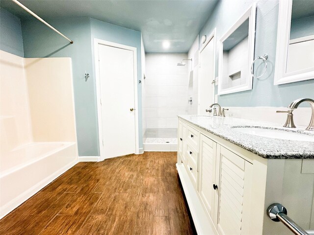 bathroom featuring hardwood / wood-style flooring, vanity, and tiled shower