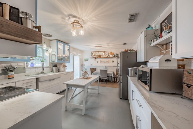 kitchen featuring white cabinets, appliances with stainless steel finishes, and hanging light fixtures