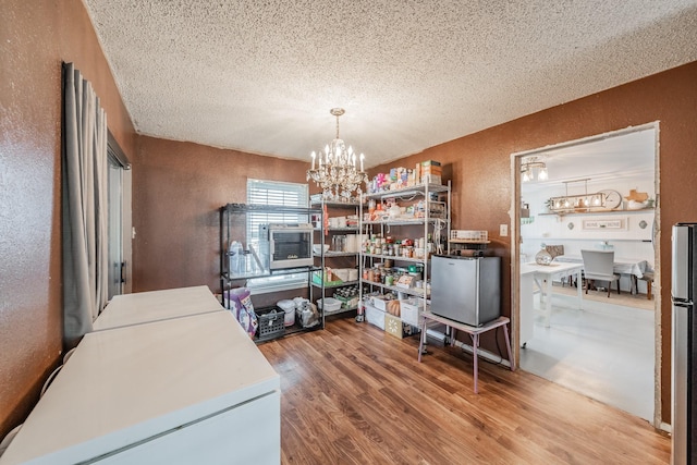 interior space featuring washer and clothes dryer, wood-type flooring, a textured ceiling, and an inviting chandelier