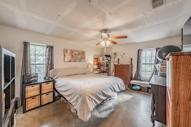 bedroom featuring multiple windows, ceiling fan, and concrete flooring