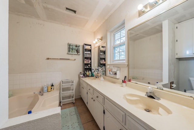 bathroom with tile patterned flooring, a relaxing tiled tub, toilet, and vanity