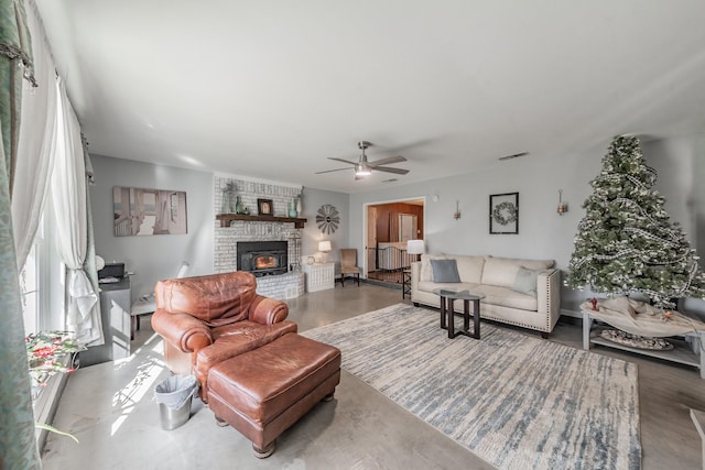 living room featuring concrete flooring, ceiling fan, and a fireplace